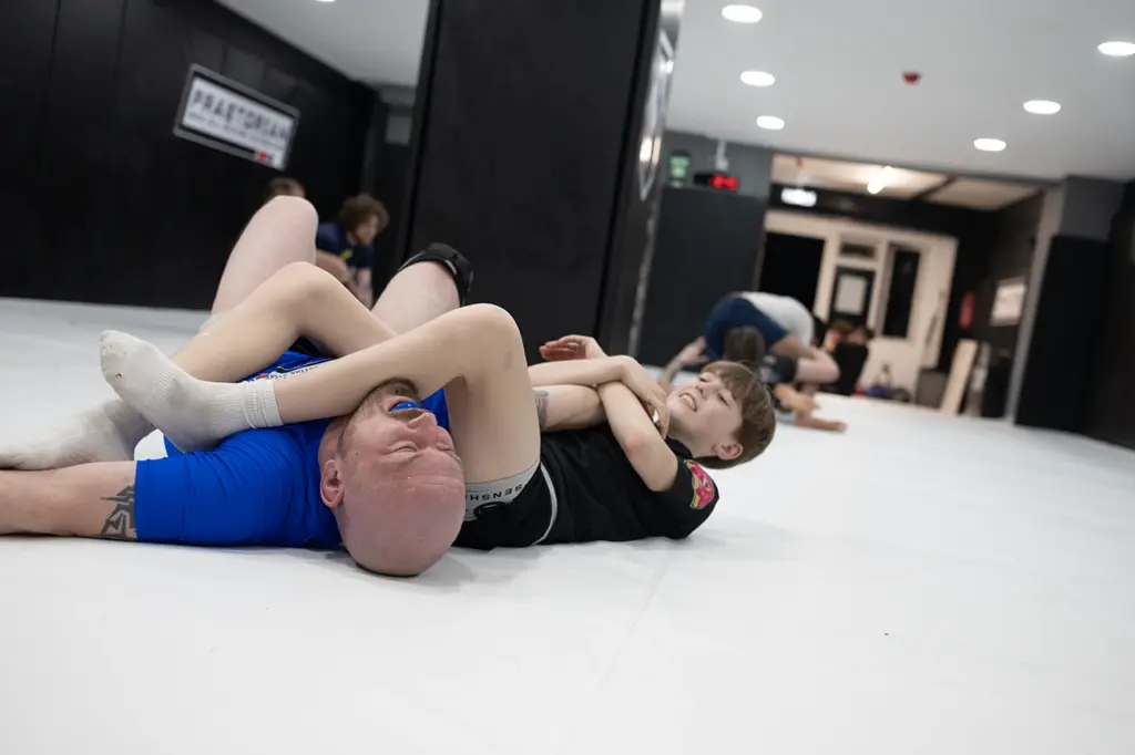 Teen member applying an armbar to his father during martial arts training at Praetorian MMA