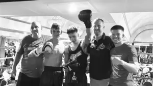 Jack Cowley standing in the ring with his Praetorian MMA coaches after his fight